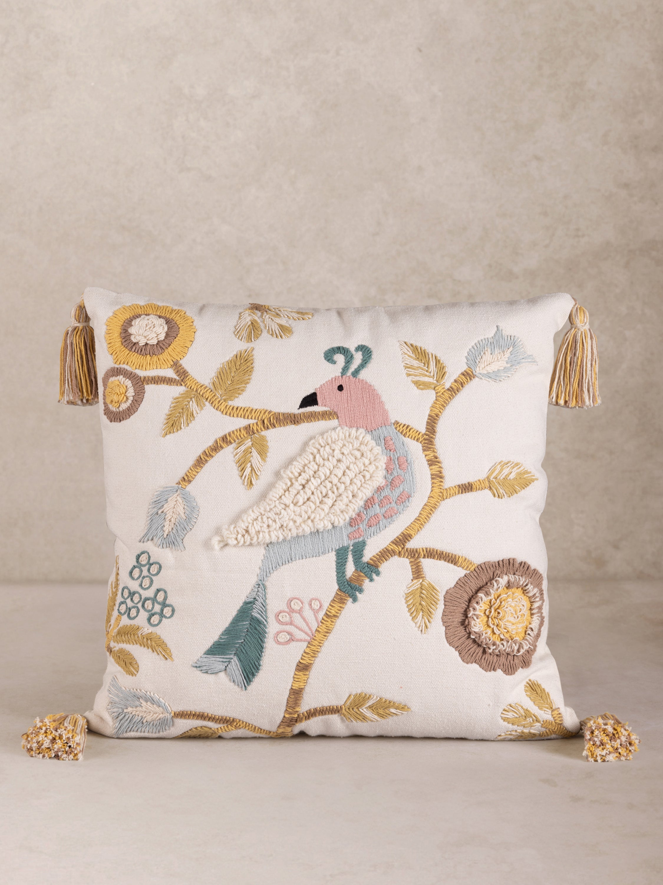 Hand-Embroidered Bird Throw Pillow with Tassel Accents – A beautifully crafted decorative pillow featuring an intricately stitched bird perched on a floral branch, adorned with soft pastel hues and tassels on each corner